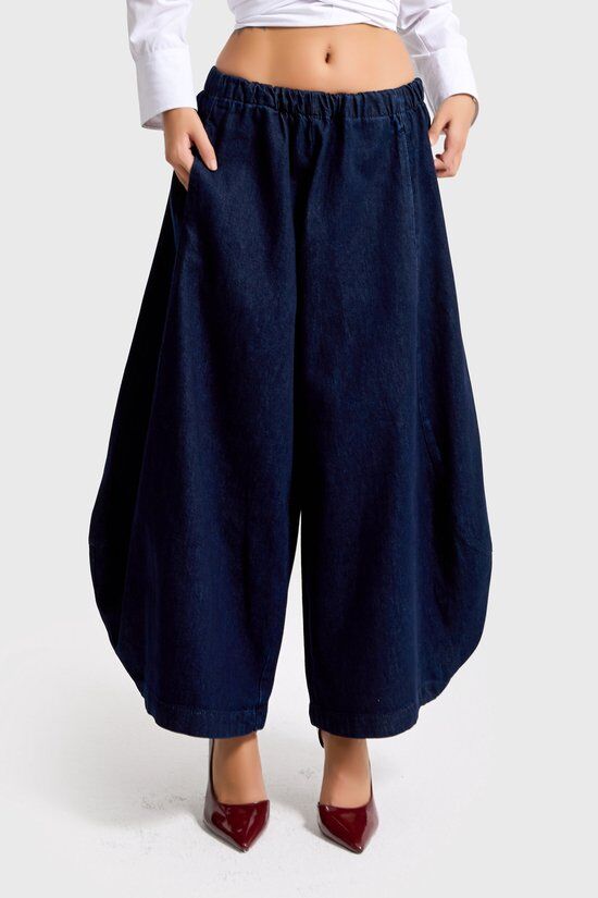 Donkerblauwe wijde denim broek met elastische tailleband en steekzakken, gedragen met bordeauxrode pumps.