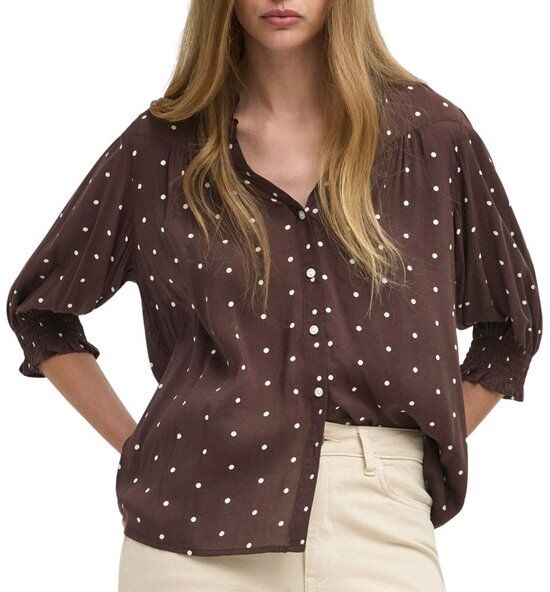 Bruine blouse met witte stippen en driekwart mouwen, gedragen door een model.